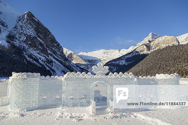 Ein wunderschönes Eisschloss mit einer kanadischen Flagge wurde aus Eisblöcken geschnitzt und auf dem zugefrorenen See zum Schlittschuhlaufen und für Touristenfotos im Fairmont Chateau Lake Louise und im Banff National Park aufgebaut; Lake Louise  Alberta  Kanada'.