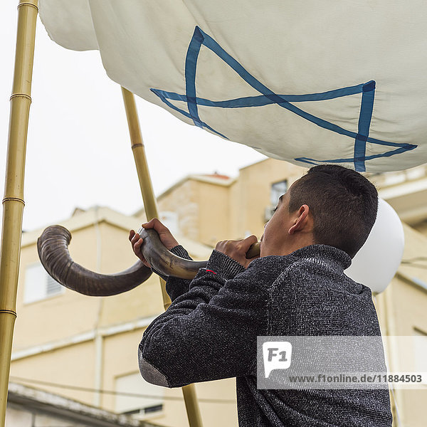 Ein junger Mann steht unter einer israelischen Flagge und bläst ein Schofar während einer Bar-Mizwa-Feier; Safed  Israel'.