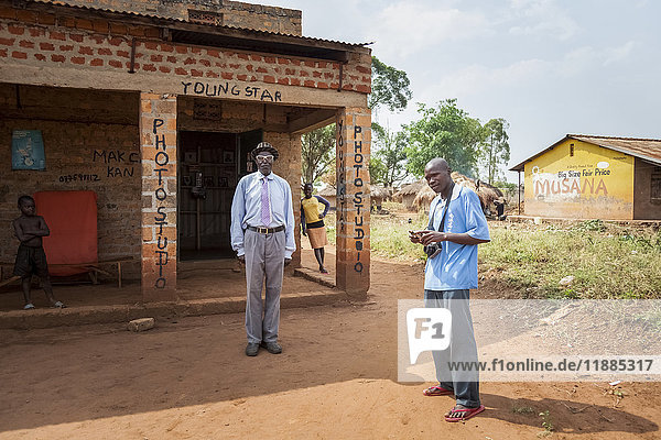 Ein Fotograf mit Kamera steht vor dem Gebäude eines Fotostudios: Uganda
