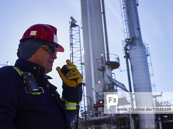 Handwerker  der bei der Arbeit in einer Raffinerie in ein Funkgerät spricht; Edmonton  Alberta  Kanada'.