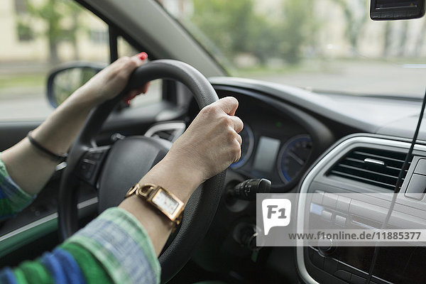 Abgeschnittenes Bild einer Frau  die eine Armbanduhr trägt und ein Auto fährt.