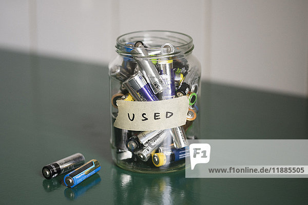 Hochwinkelansicht der Batterien im Glas mit USED-Etikett auf dem Tisch
