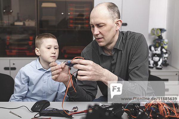Teacher assisting student in making machinery at table in classroom