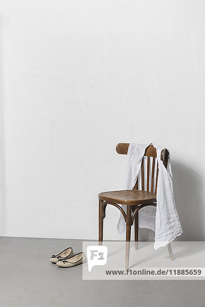 Stoff auf Holzstuhl mit Schuh gegen die weiße Wand