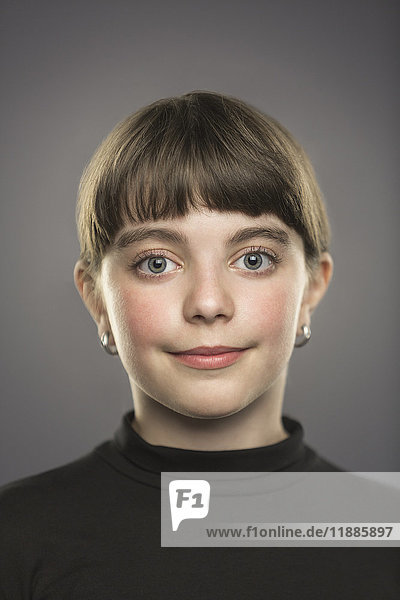 Portrait of smiling girl with bangs against gray background