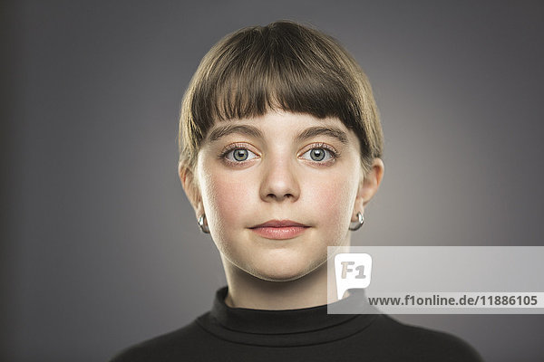 Portrait of smiling girl with gray eyes against gray background