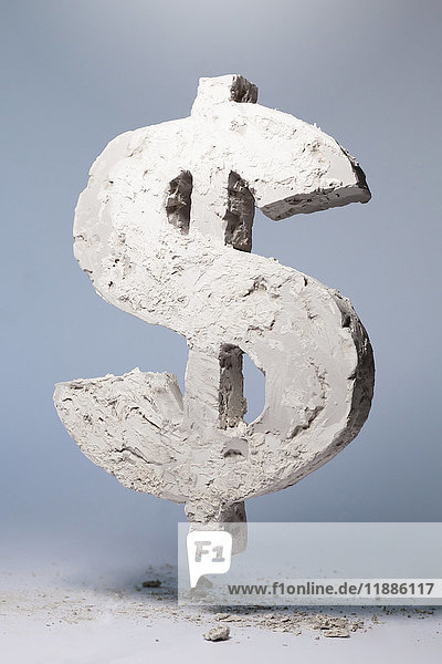 Dollarzeichen aus Steinmaterial schwebend auf grauem Hintergrund