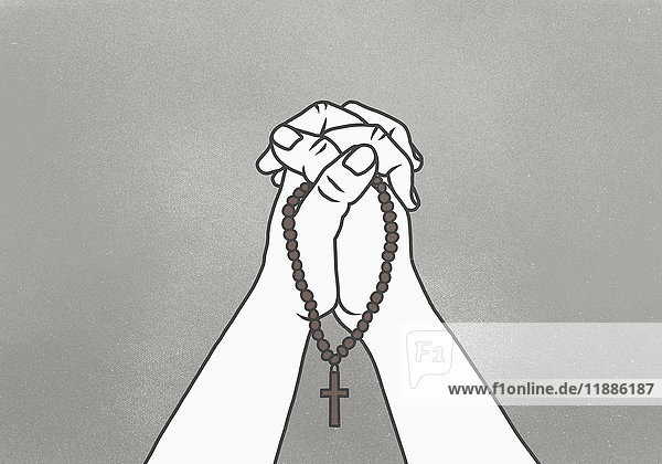 Abgeschnittenes Bild von umklammerten Händen  die Rosenkranz-Perlen vor grauem Hintergrund halten.