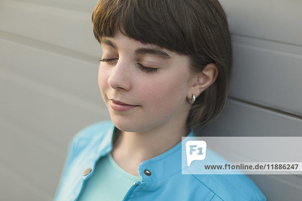 Close-up of girl with closed eyes leaning on wall