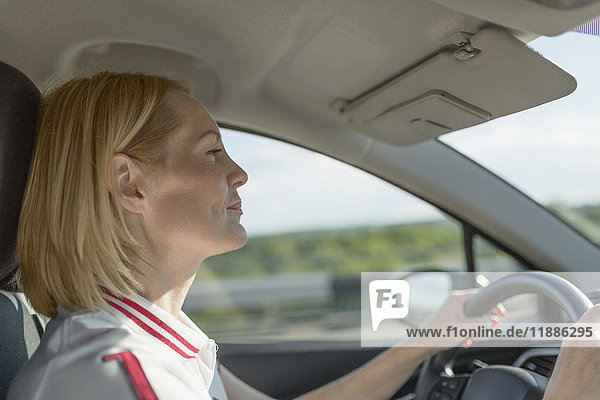 Seitenansicht der selbstbewussten reifen Frau beim Autofahren an einem sonnigen Tag