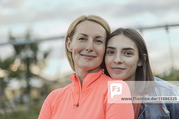 Porträt der lächelnden Mutter und Tochter gegen den Himmel im Park