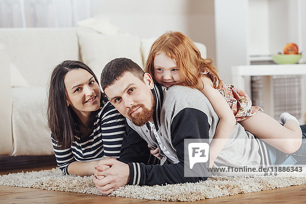 Portrait of smiling family lying on carpet at home