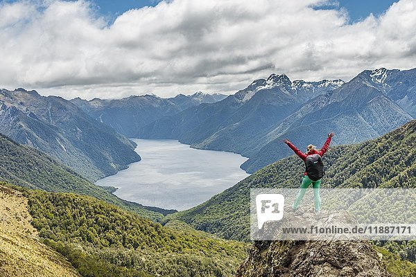 Wanderin mit Blick auf den South Fiord des Lake Te Anau,  Arme ausgestreckt,  Southern Alps im Rücken,  Wanderweg Kepler Tack,  Fiordland National Park,  Southland,  Neuseeland,  Ozeanien