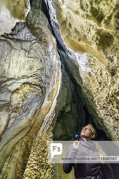 Woman lighting a cave with flashlight  limestone cave  Luxmore Cave  Kepler Track  Fiordland National Park  South Island  New Zealand  Oceania
