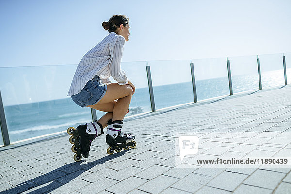 Junge Frau mit Inline-Skates auf der Strandpromenade an der Küste