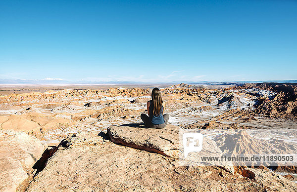 Chile  Atacama-Wüste  Rückansicht der auf einem Felsen sitzenden Frau mit Blick auf die Aussicht