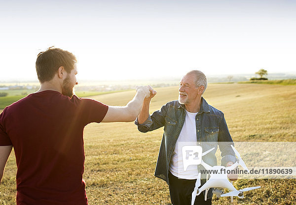 Senior Vater und sein erwachsener Sohn mit Drohne auf einem Feld