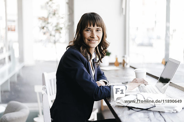 Geschäftsfrau sitzend im Café mit Laptop  lächelnd