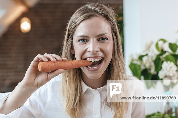 Porträt einer jungen Frau beißt Karotte