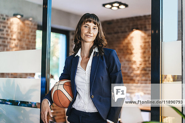 Businesswoman holding basket ball in office