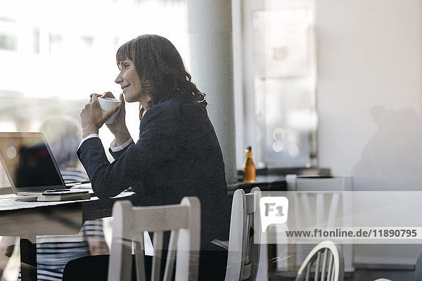 Businesswoamn mit Laptop  im Café sitzen  Kaffee trinken
