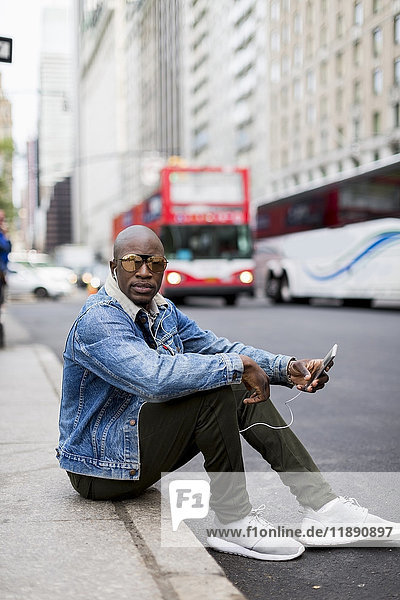 USA  New York City  Manhattan  stylish man sitting on curb