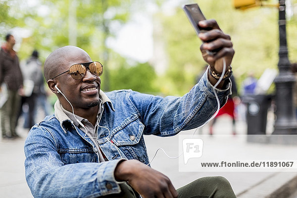 Portrait of smiling man wearing mirrored sunglasses taking selfie with smartphone