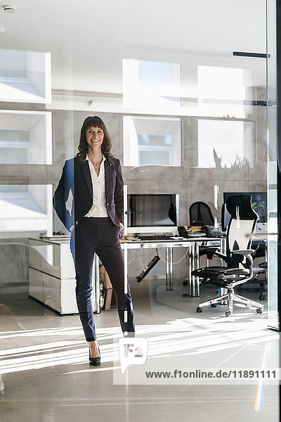 Successful businesswoman standing in office with hands in pockets