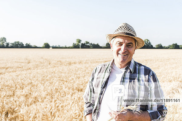 Porträt eines lachenden Seniorenbauern vor einem Feld