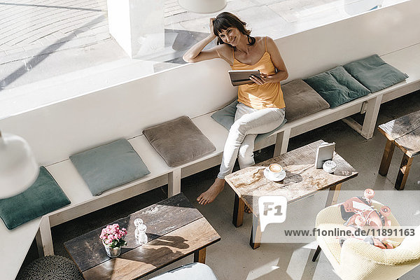 Frau mit Rollschuhen sitzend in einem Café  mit Tablet PC