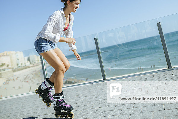 Young woman inline skating on boardwalk at the coast