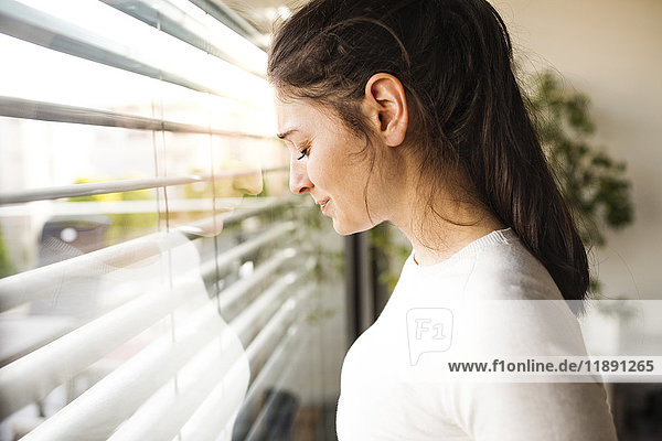 Frau zu Hause aus dem Fenster schauend