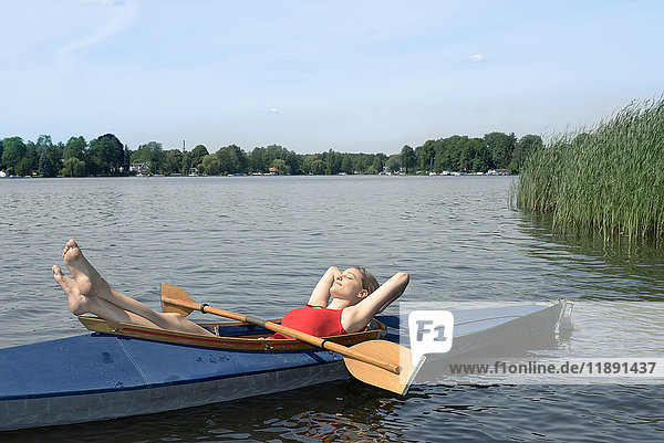 Woman sunbathing in a kayak on a lake