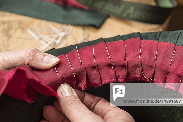 Hands folding and fastening silk ribbon using pins  inner lining of a wool felt hat  hatmaker workshop  Bad Aussee  Styria  Austria  Europe