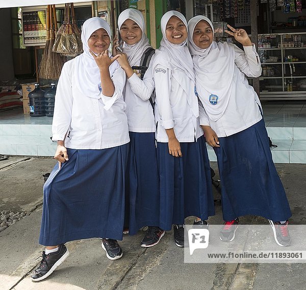 Cheerful Muslim schoolgirls in school uniforms posing for camera  Yogyakarta  Java  Indonesia  Asia