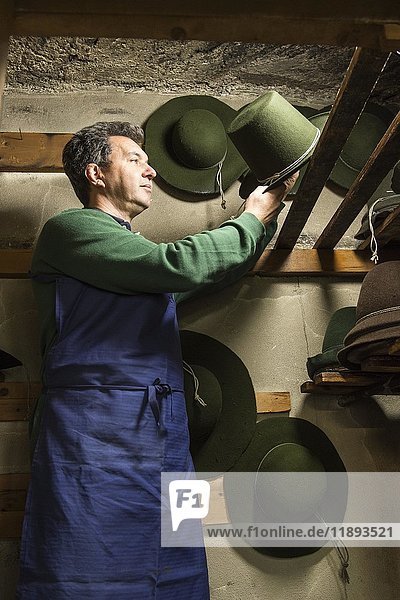 Hutmacher  der einen Wollfilzhut mit Formschnur zum Trocknen auf Holzbretter im Trockenraum legt  Hutmacherwerkstatt  Bad Aussee  Steiermark  Österreich  Europa
