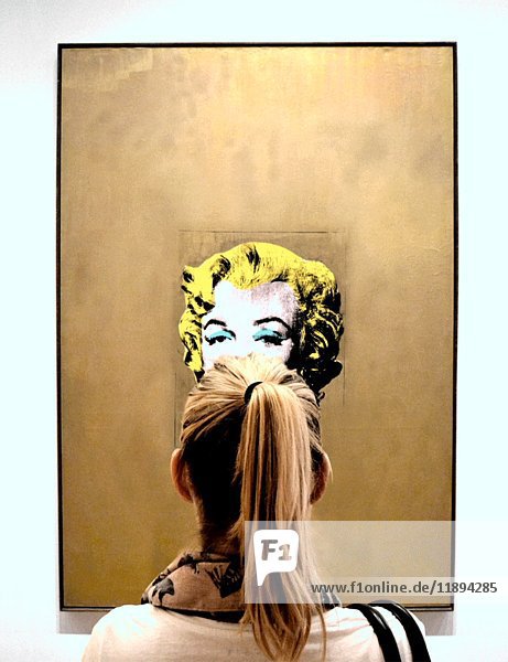 Junge Frau betrachtet Marilyn Monroe-Porträt im Museum