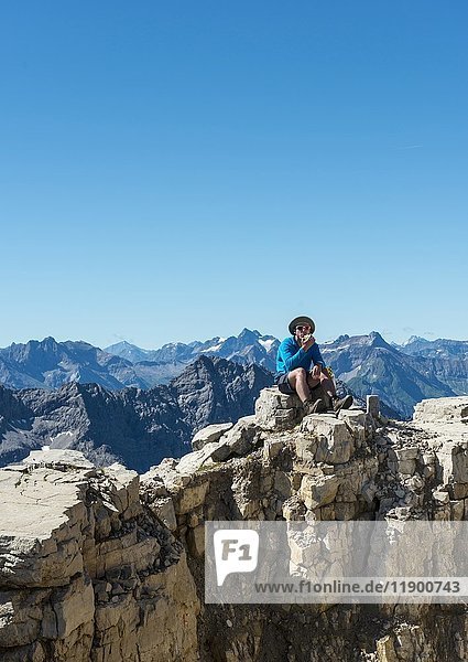 Wanderer schaut auf Landschaft  isst Apfel  Berge und Alpen  Gipfel des Hochvogel  Allgäu  Allgäuer Hochalpen  Bayern  Deutschland  Europa