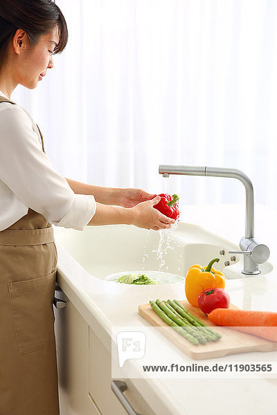Japanerin wäscht Gemüse in der Küche