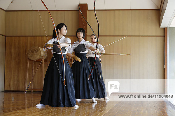 Multi-ethnic group of traditional archery athletes practicing