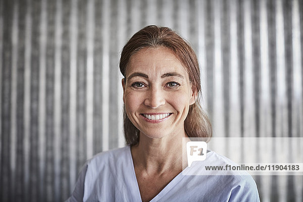 Porträt der lächelnden Geschäftsfrau gegen die Wellblechwand im Kreativbüro