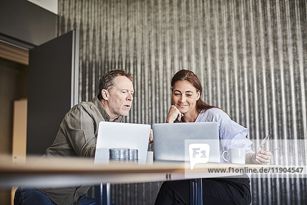 Reife Geschäftskollegen mit Laptop im Vorstandszimmer des Kreativbüros
