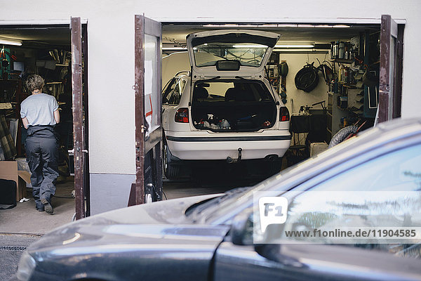 Rear view of female mechanic seen through doorway of auto repair shop