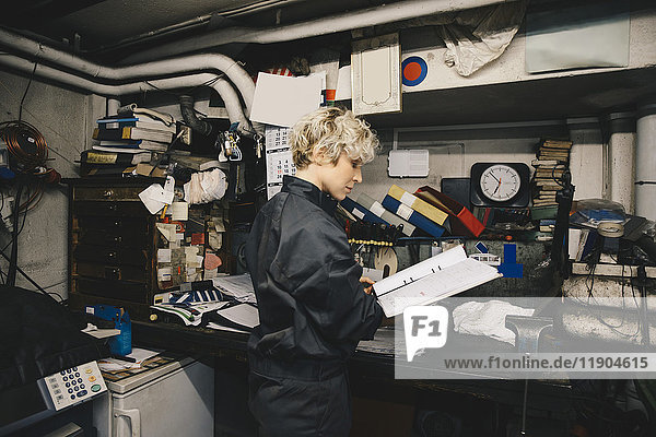 Seitenansicht der Mechanikerin beim Lesen des Dokuments in der Kfz-Werkstatt