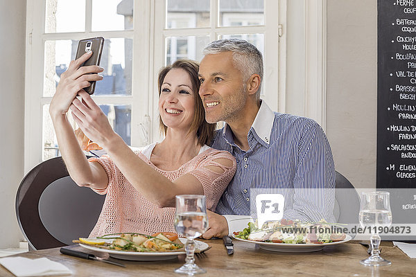 Kaukasisches Paar posiert für Handy-Selfie im Restaurant