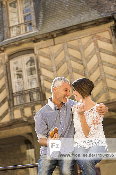 Kaukasisches Paar isst Brot auf einem Geländer