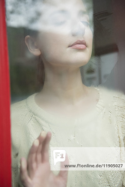Caucasian woman daydreaming behind foggy window