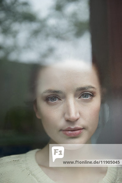 Ernste kaukasische Frau hinter nebligem Fenster