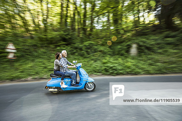 Kaukasisches Paar fährt blauen Motorroller