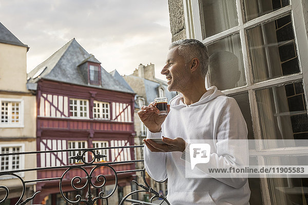 Kaukasischer Mann genießt Espresso auf einem Balkon in der Stadt